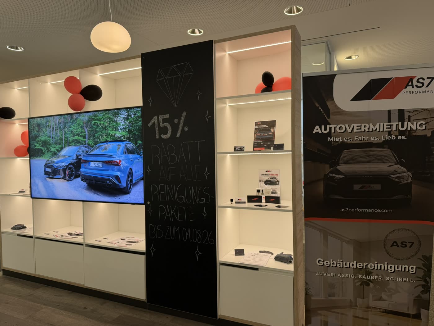 AS7-Ausstellungsfläche in der Sparkasse Darmstadt und Dieburg: beleuchtete Vitrinenwand mit Bildschirm und AS7-Banner